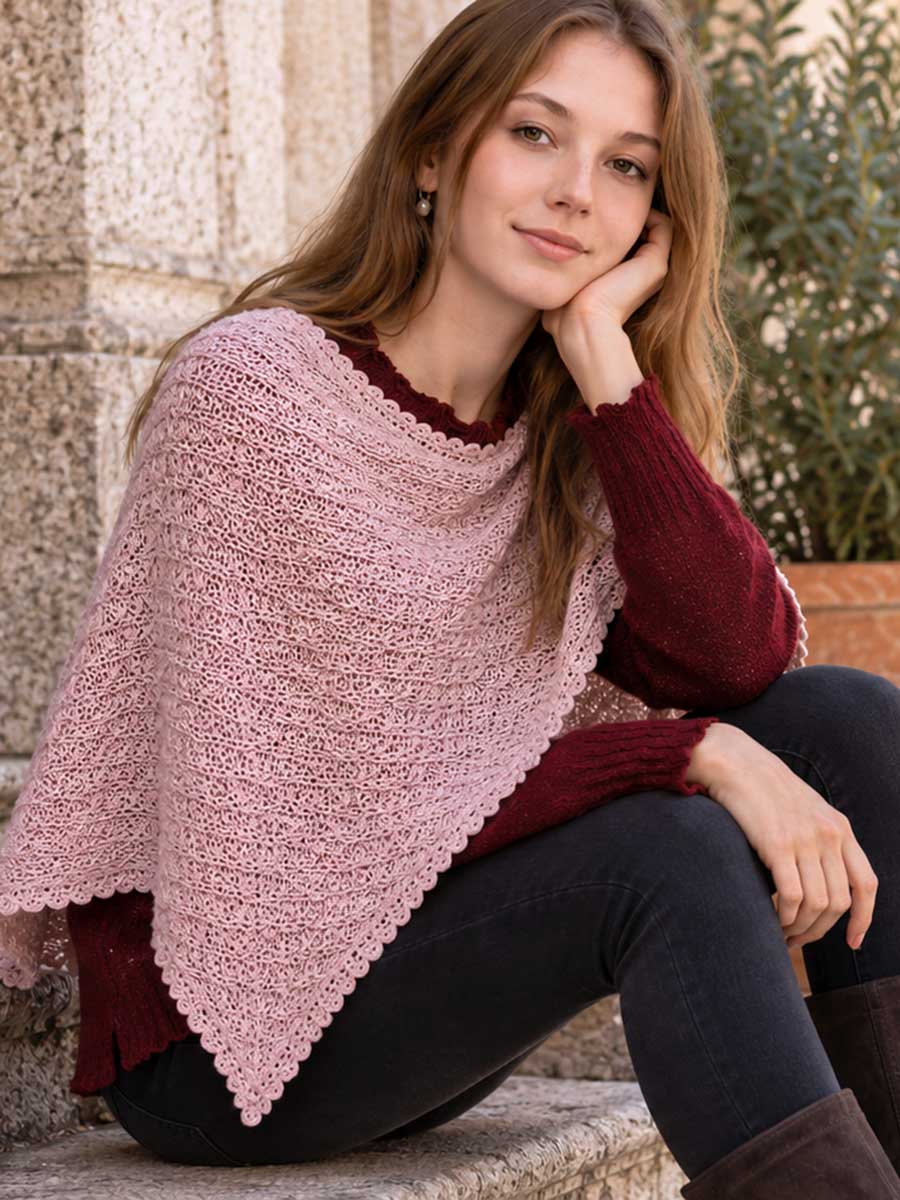Frau mit leichtem Poncho in Altrosa über einem bordeauxroten Pullover